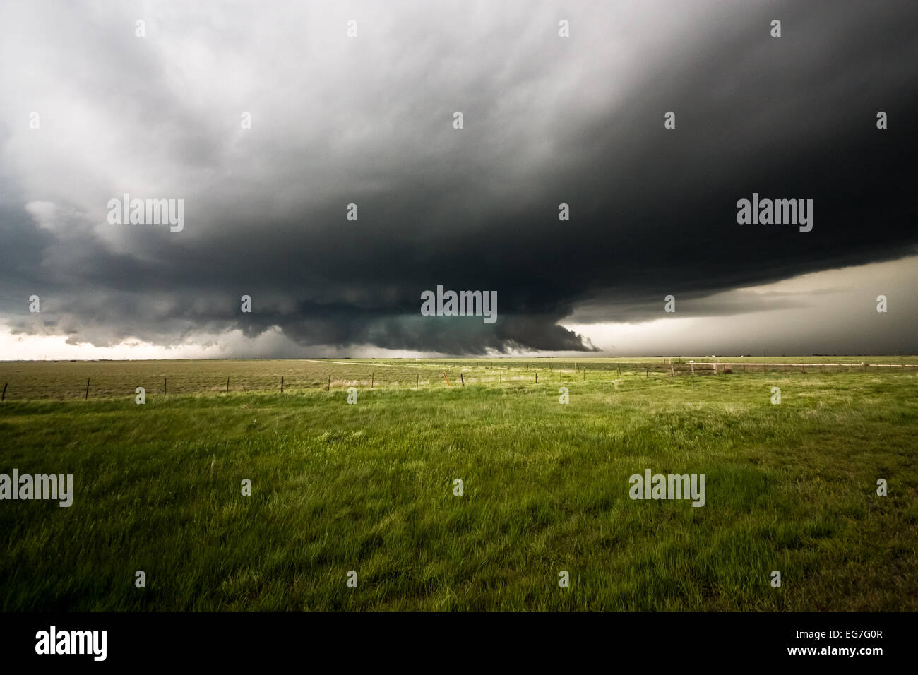 A powerful tornado warned supercell thunderstorm rolls across the Texas landscape with a large wall cloud and green hail core Stock Photo