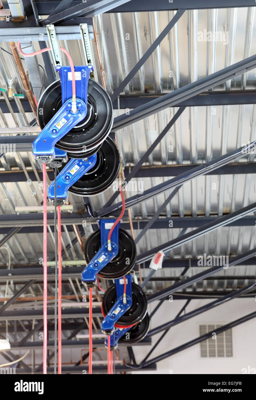 A row of hose reels hanging from the ceiling of an automotive repair shop Stock Photo