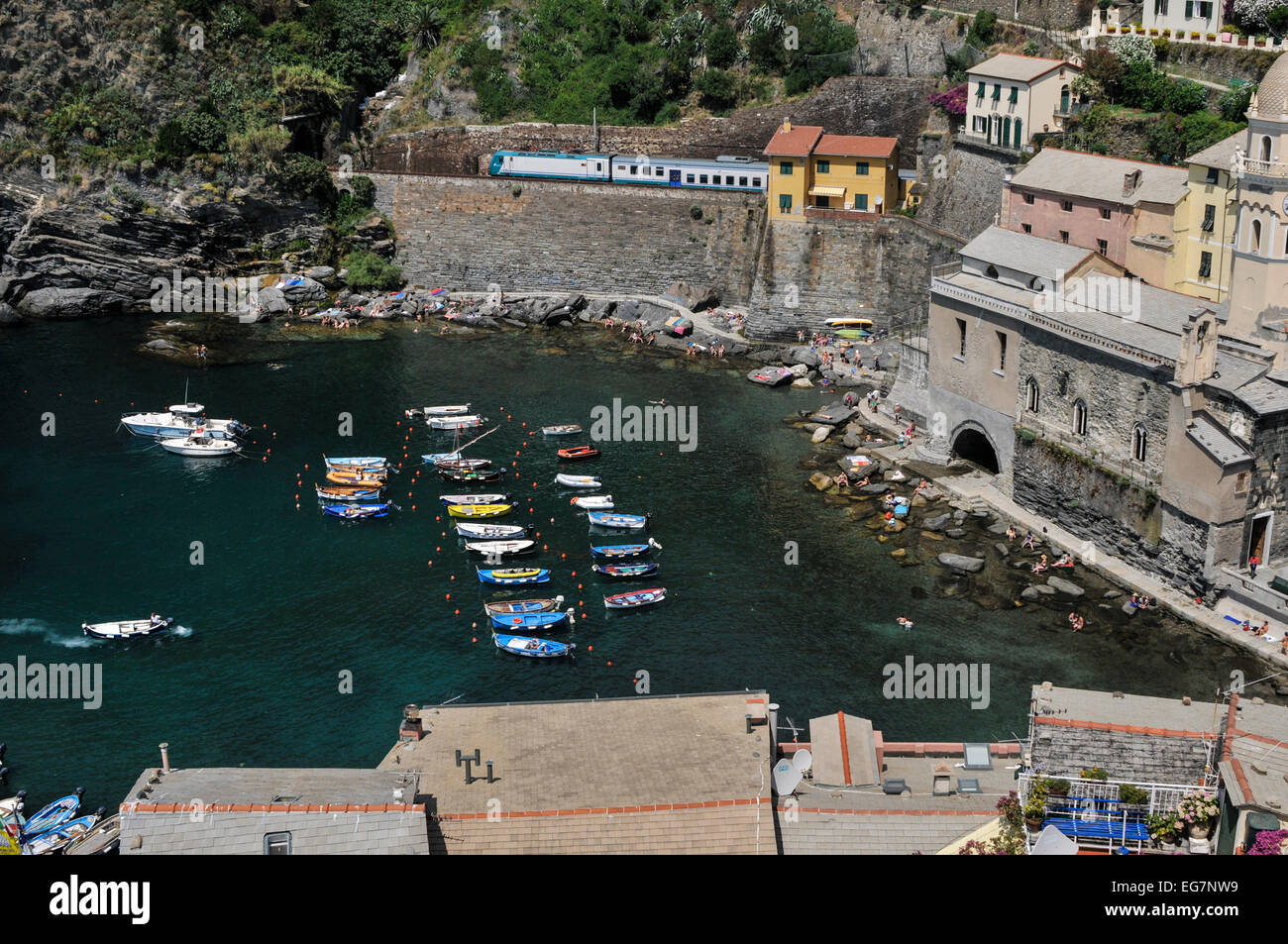 The harbour of Vernazza with boats and swimmers, and the train that goes to all the villages of Cinque Terre, Vernazza, Cinque T Stock Photo