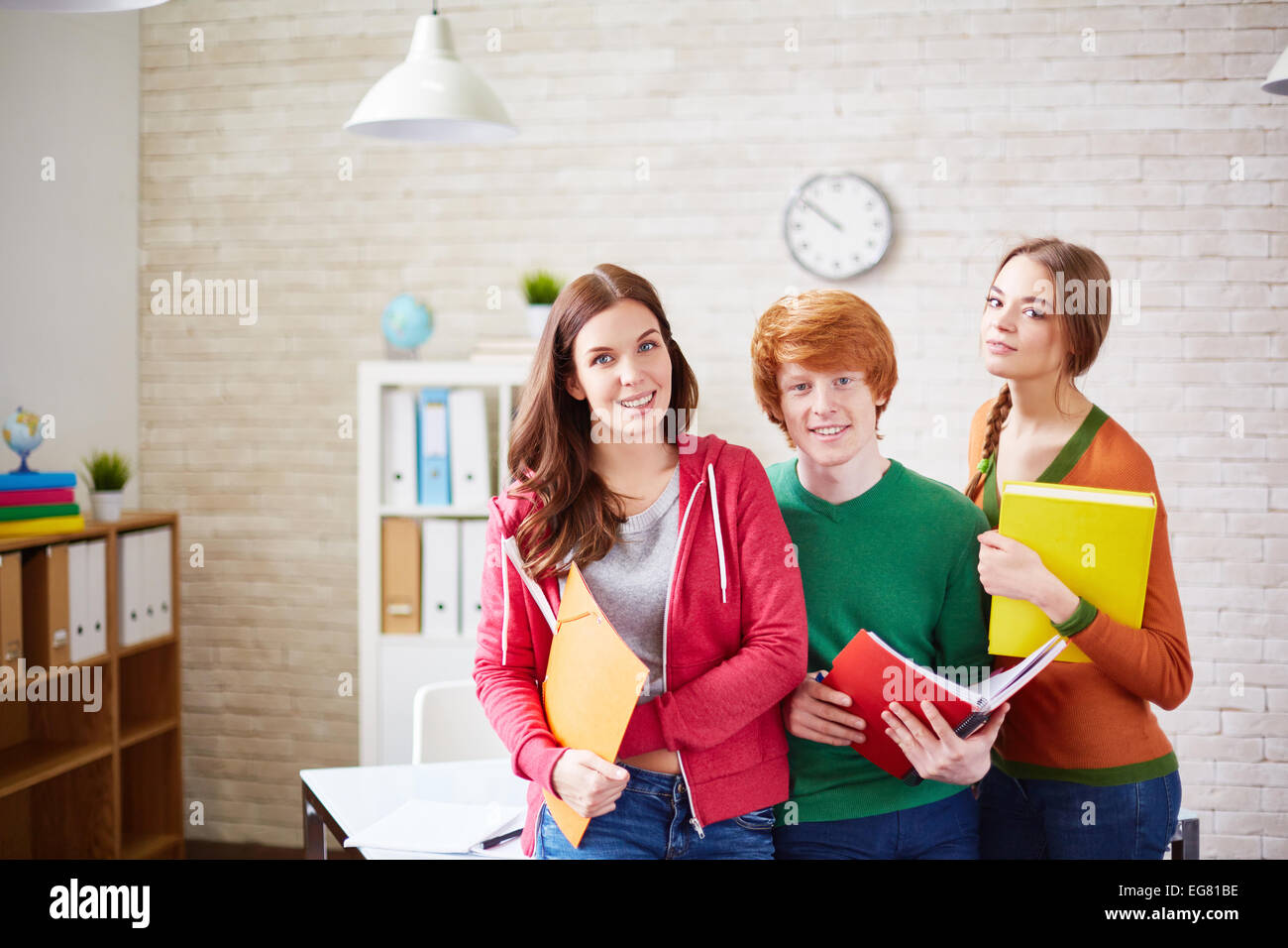 Group of students standing by desk in classroom Stock Photo - Alamy