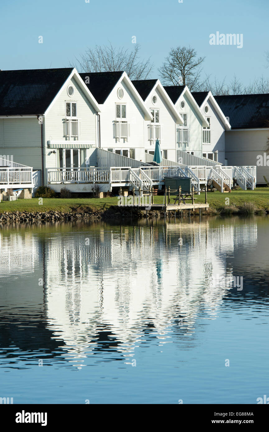 Clapperboard style houses along a lake at the watermark club, Cotswold Water Park, Gloucestershire, England Stock Photo