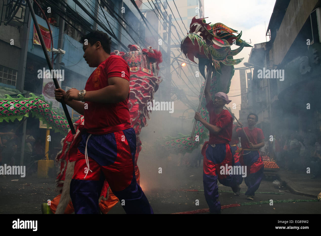 Performers run along Ongpin Street in Binondo with their dragon as firecrackers explode. Thousands of people joined in the celebration of the Lunar New Year in Binondo, Manila. The Filipino-Chinese community, in the oldest china town in the world, welcomed the year of the wooden sheep with dragon and lion dances. © Gerard Seguia/Pacific Press/Alamy Live News Stock Photo