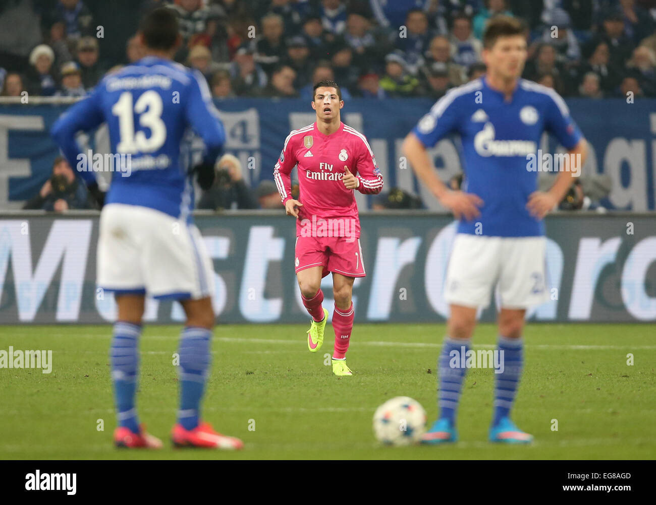 Gelsenkirchen, Germany. 18th Feb, 2015. Cristiano Ronaldo (Real Madrid) celebrates his 1:0 goal against Schalke during the UEFA Champions League Round of 16, first leg soccer match between FC Schalke 04 and Real Madrid in Gelsenkirchen, Germany, 18 February 2015. Schalke's Klaas-Jan Huntelaar (r) and Eric Maxim Choupo-Moting (l)stand in the foreground. Real Madrid won 2-0. Photo: Friso Gentsch/dpa/Alamy Live News Stock Photo