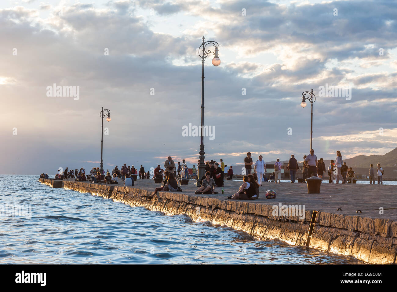 Trieste, Italy - Tourists and locals enjoy the sunset on the Molo Audace pier Stock Photo