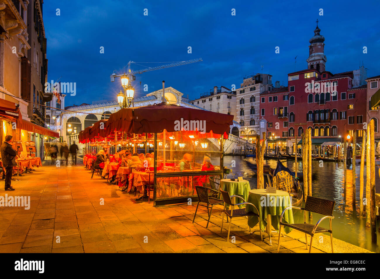 Night view of an outdoor cafe restaurant along Grand Canal with Rialto bridge behind, Venice, Veneto, Italy Stock Photo