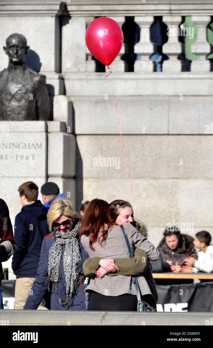 London, England, UK. Two girls in Trafalgar Square embracing, with a balloon Stock Photo