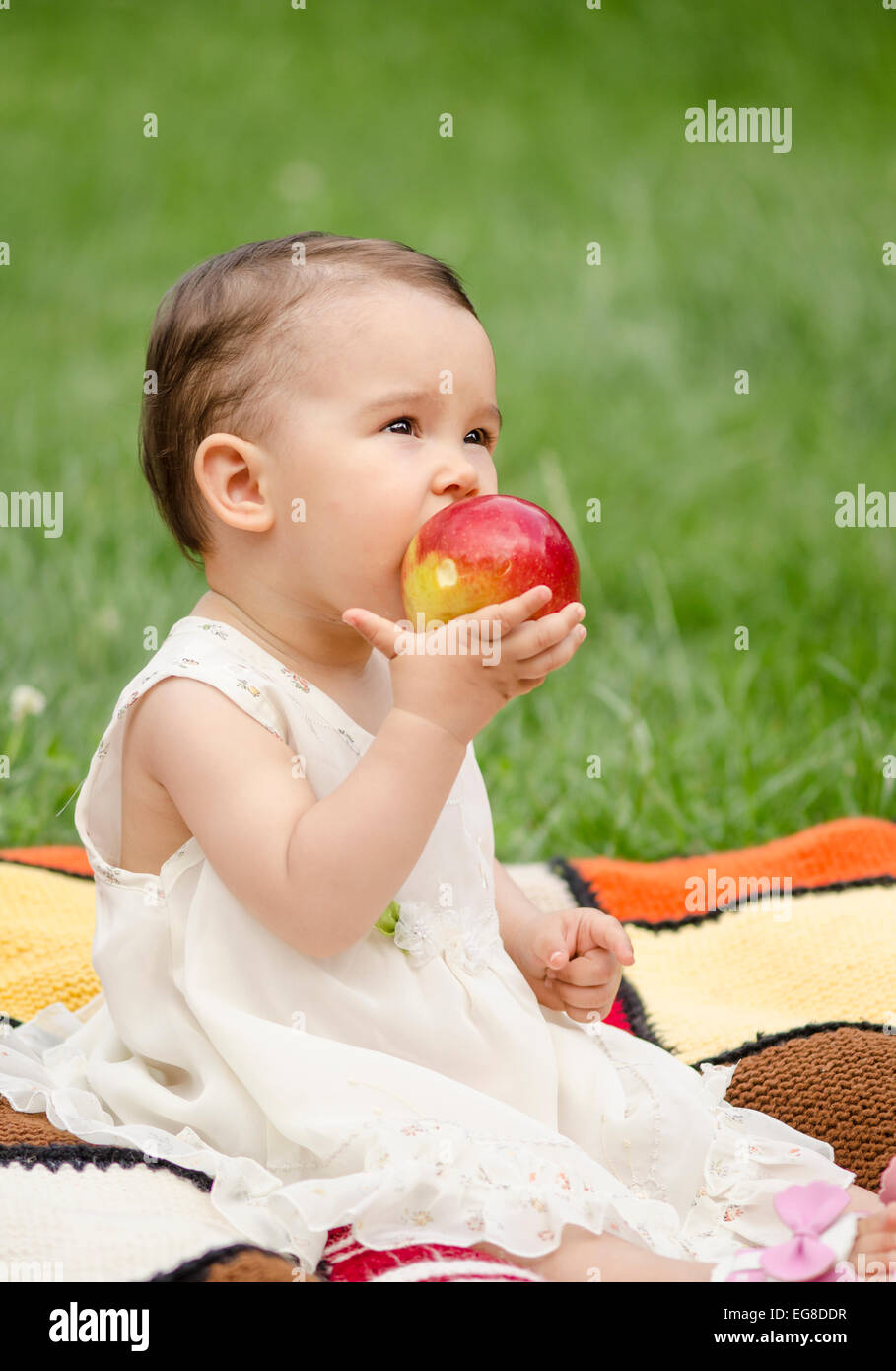 Cute little girl eating a red apple Stock Photo