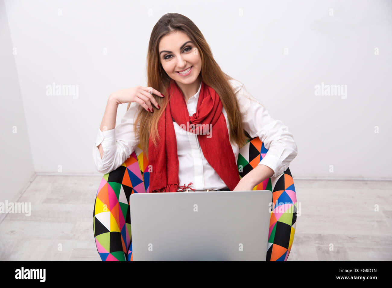 Happy woman sitting on the colourful chair with laptop Stock Photo - Alamy