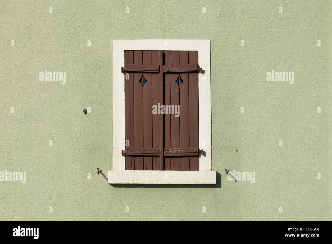 Closed shuttered wooden window on green painted wall in Lahr, Germany Stock Photo
