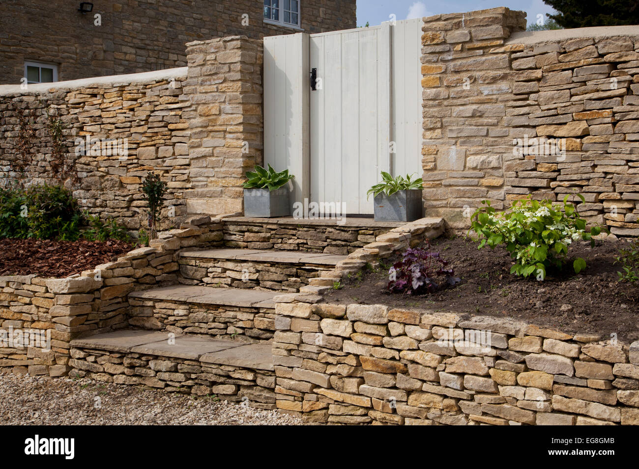 Dry stone wall and steps with gateway into English garden,Oxfordshire,England Stock Photo