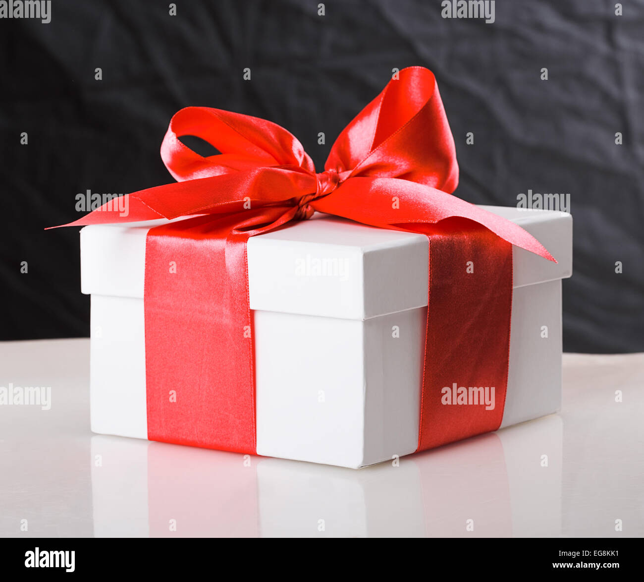 white gift box with red ribbon bow on black background Stock Photo - Alamy