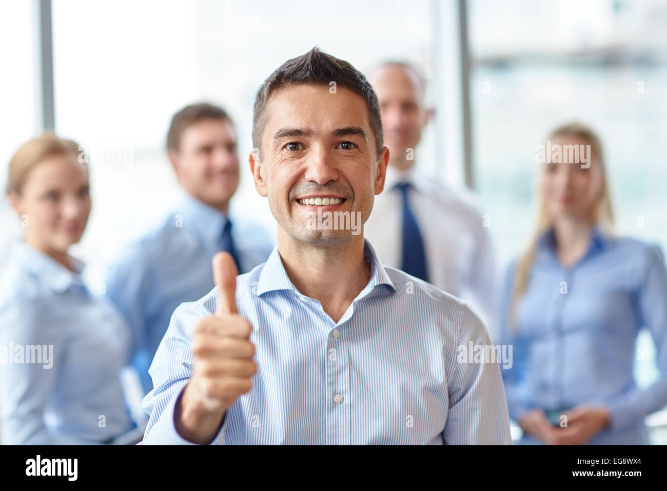 smiling business team showing thumbs up in office Stock Photo - Alamy