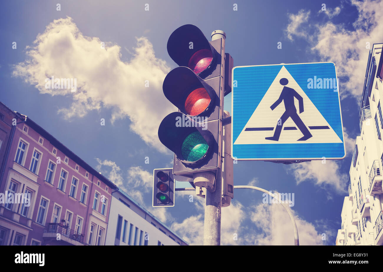 Retro filtered photo of traffic lights and pedestrian crossing sign in a city. Stock Photo