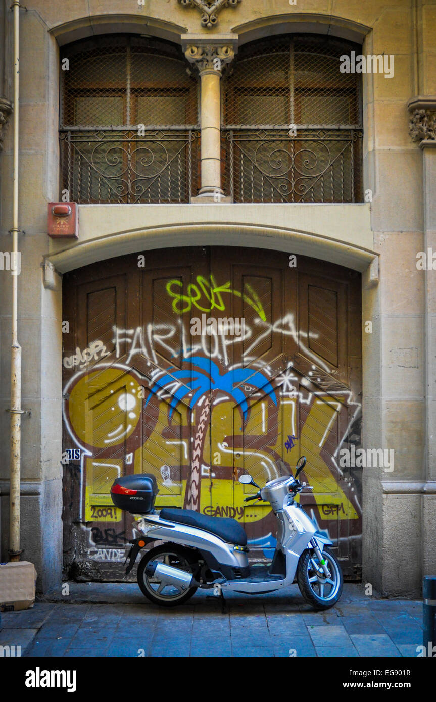 motor scooter in front of graffitied doorway Barcelona Spain Stock