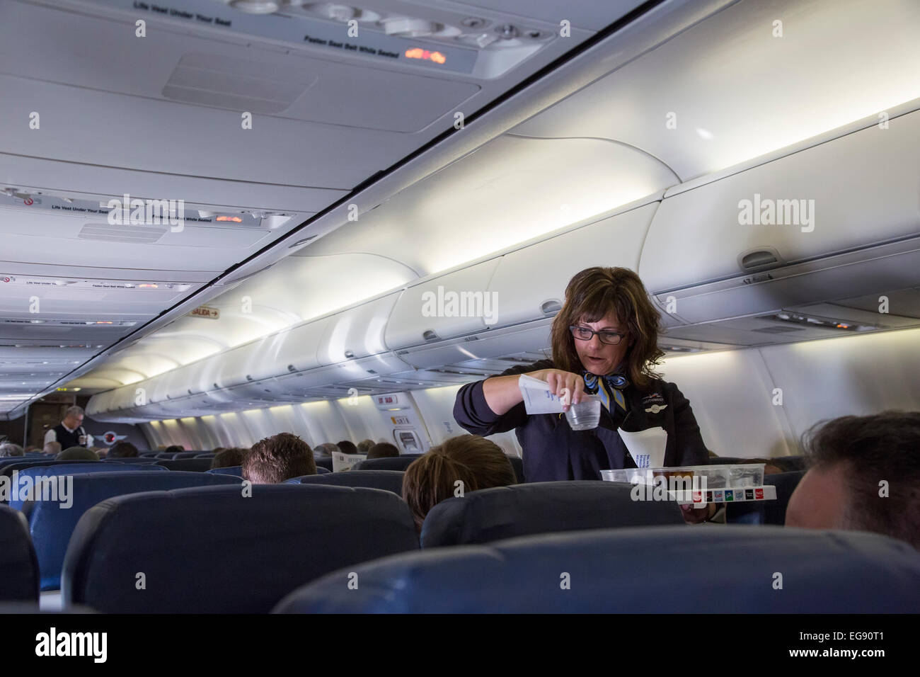 Chicago, Illinois - A Southwest Airlines flight attendant serves drinks to passengers on a flight to Denver. Stock Photo