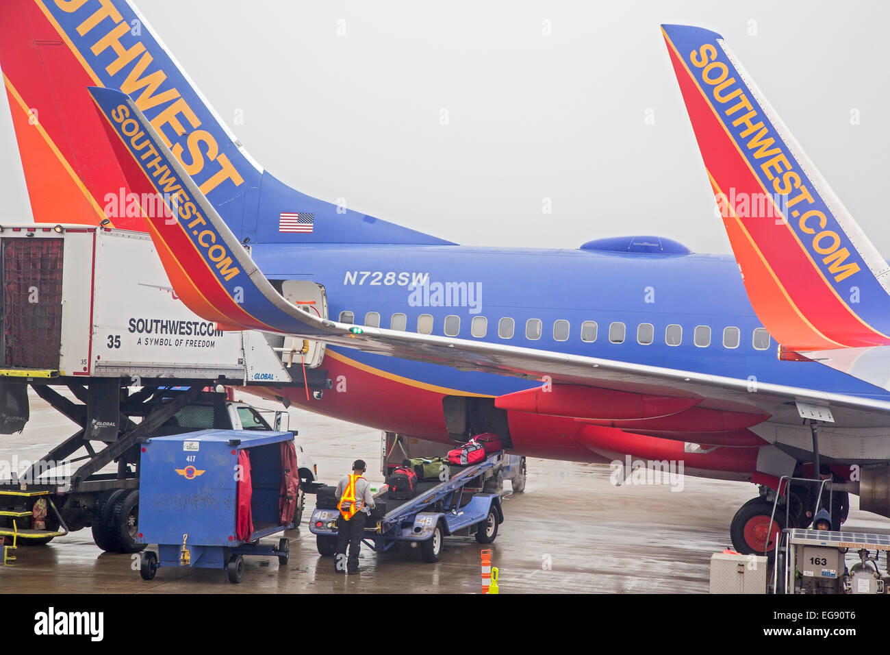 Chicago, Illinois - A member of the Southwest Airlines ground crew at Midway Airport unloads luggage from a Boeing 737. Stock Photo