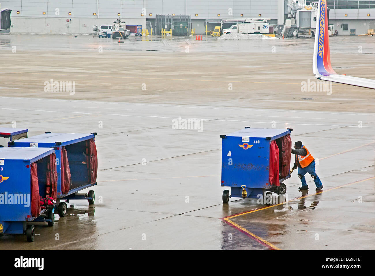 Chicago, Illinois - A member of the Southwest Airlines ground crew pushes a luggage cart on the tarmac at Midway Airport. Stock Photo