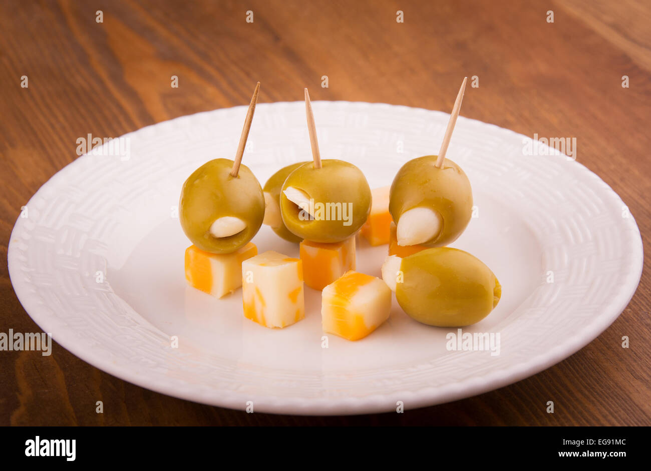 Green stuffed olives with cheese on toothpicks on a white plate Stock Photo