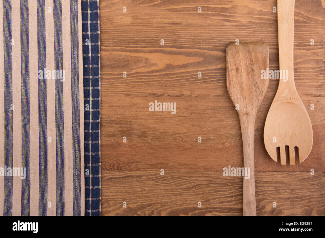 Wooden kitchen utensils and linen kitchen towels on dark wood tabletop, with copy space in the center Stock Photo
