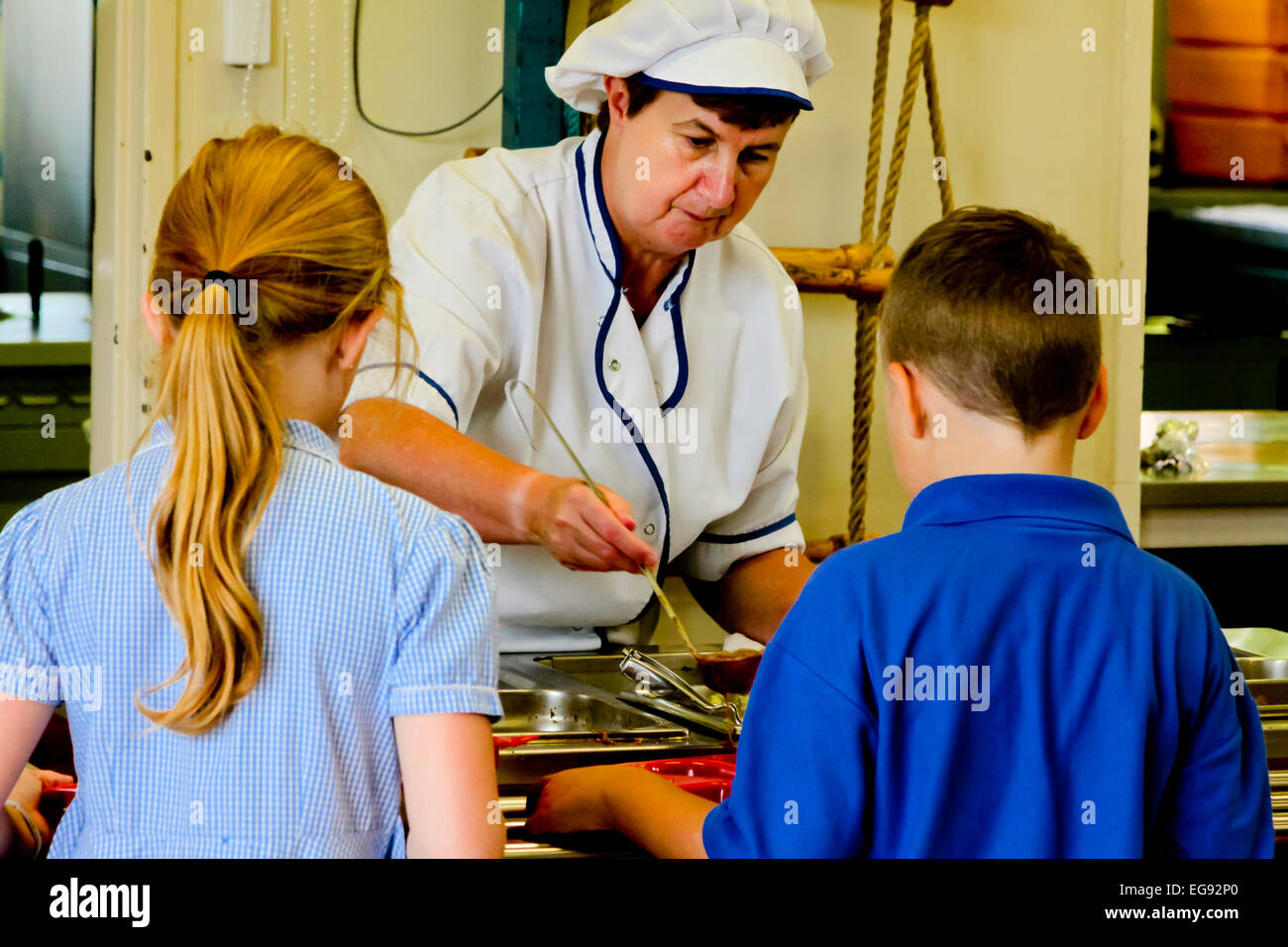 Primary school children in the UK being served midday meals cooked by staff in the school kitchen Stock Photo