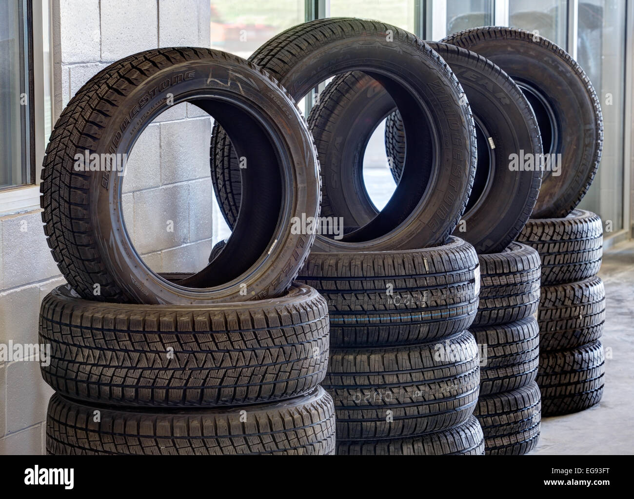 Stacks of tires, with tread patterns for various driving conditions, for sale in an automotive repair garage. Stock Photo