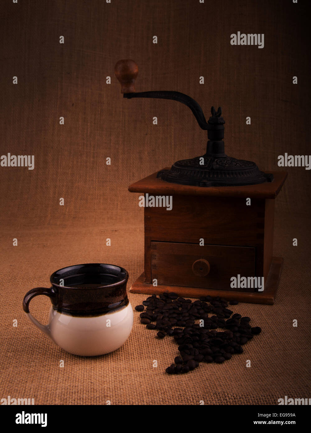 Cup of coffee with beans and an old grinder on the background, a warm toned image with vignette Stock Photo