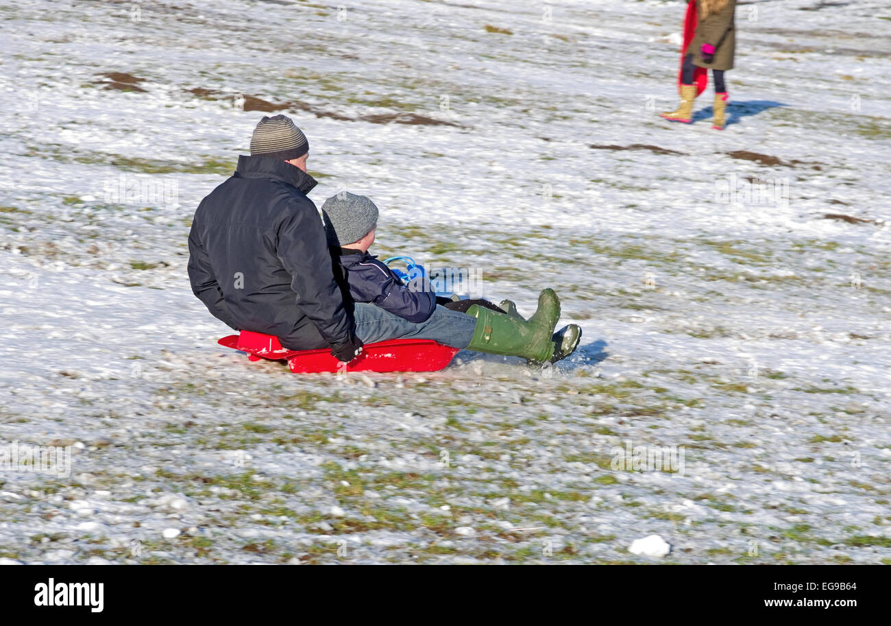 Man and boy on sledge together sledging downhill on snowy hillside Caldbeck fells, Lake District, Cumbria, England UK Stock Photo