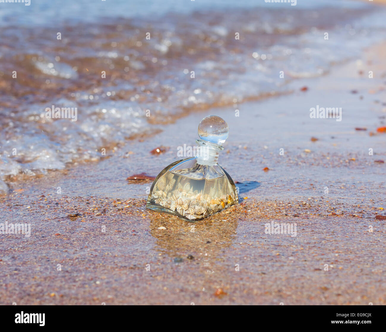A bottle with seashells embedded in the sand on the beach Stock Photo