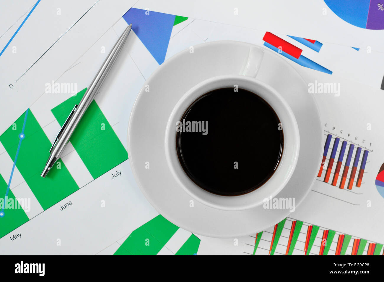 high-angle shot of a cup of coffee on a desk full of charts in the office Stock Photo
