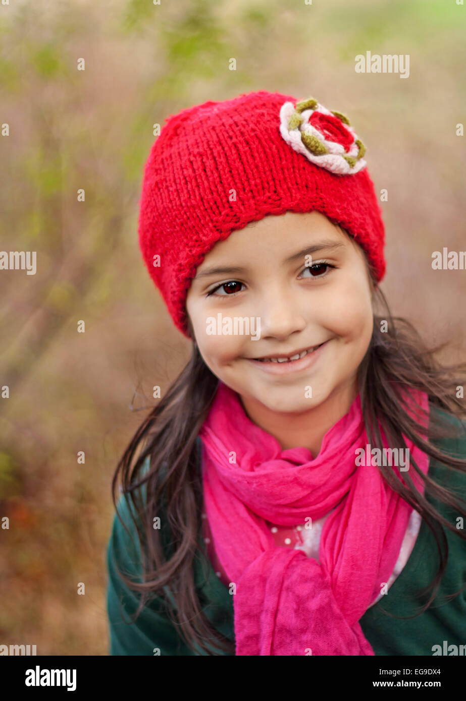 Girl (4-5) wearing a red knit hat smiling outdoors Stock Photo