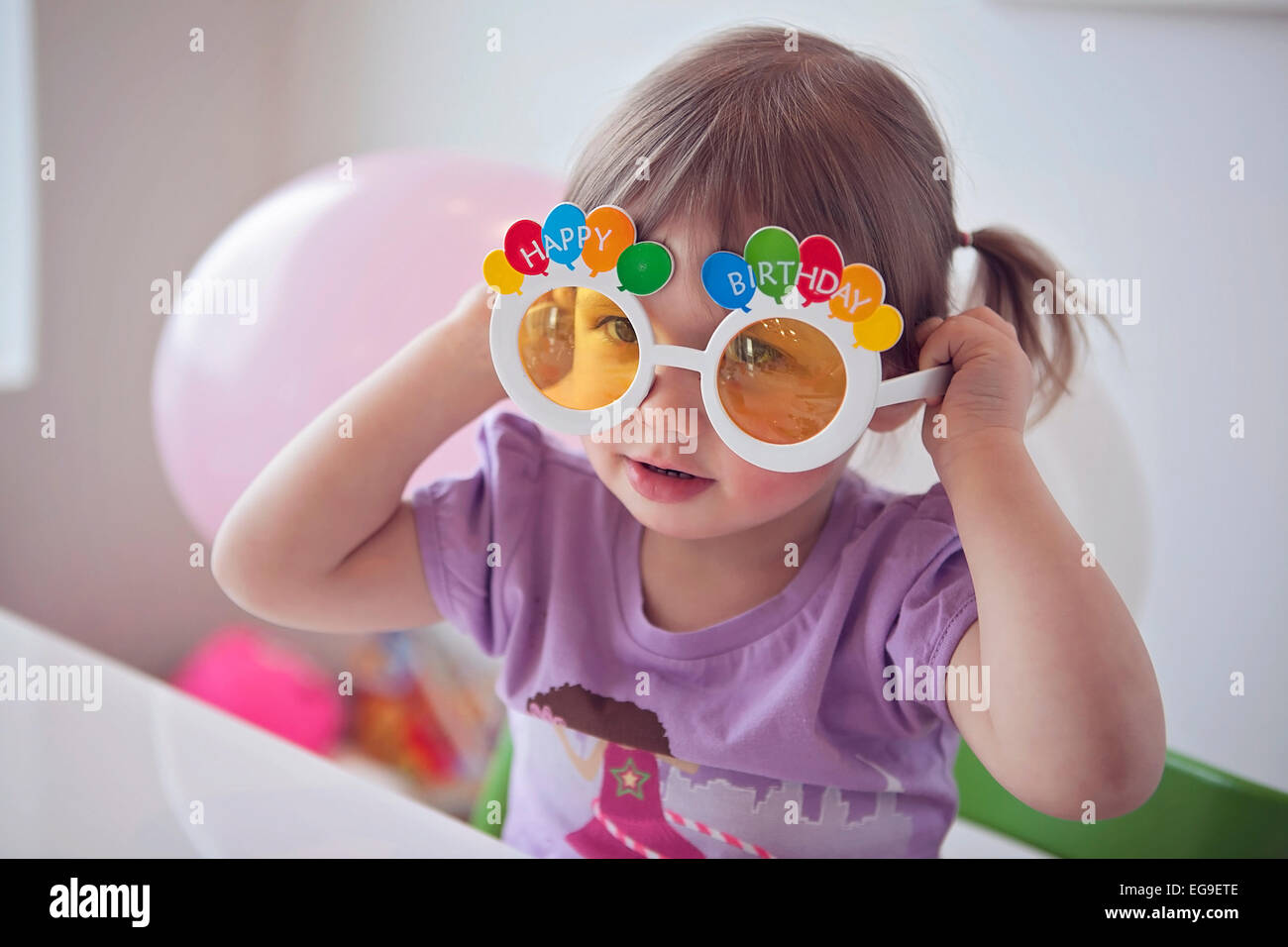 Little girl (2-3) wearing happy birthday glasses Stock Photo