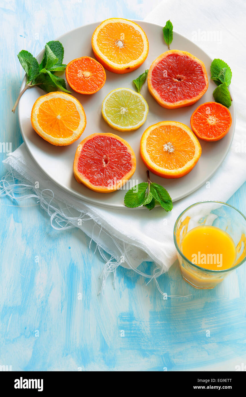 Slices of citrus fruits on plate and glass of juice Stock Photo
