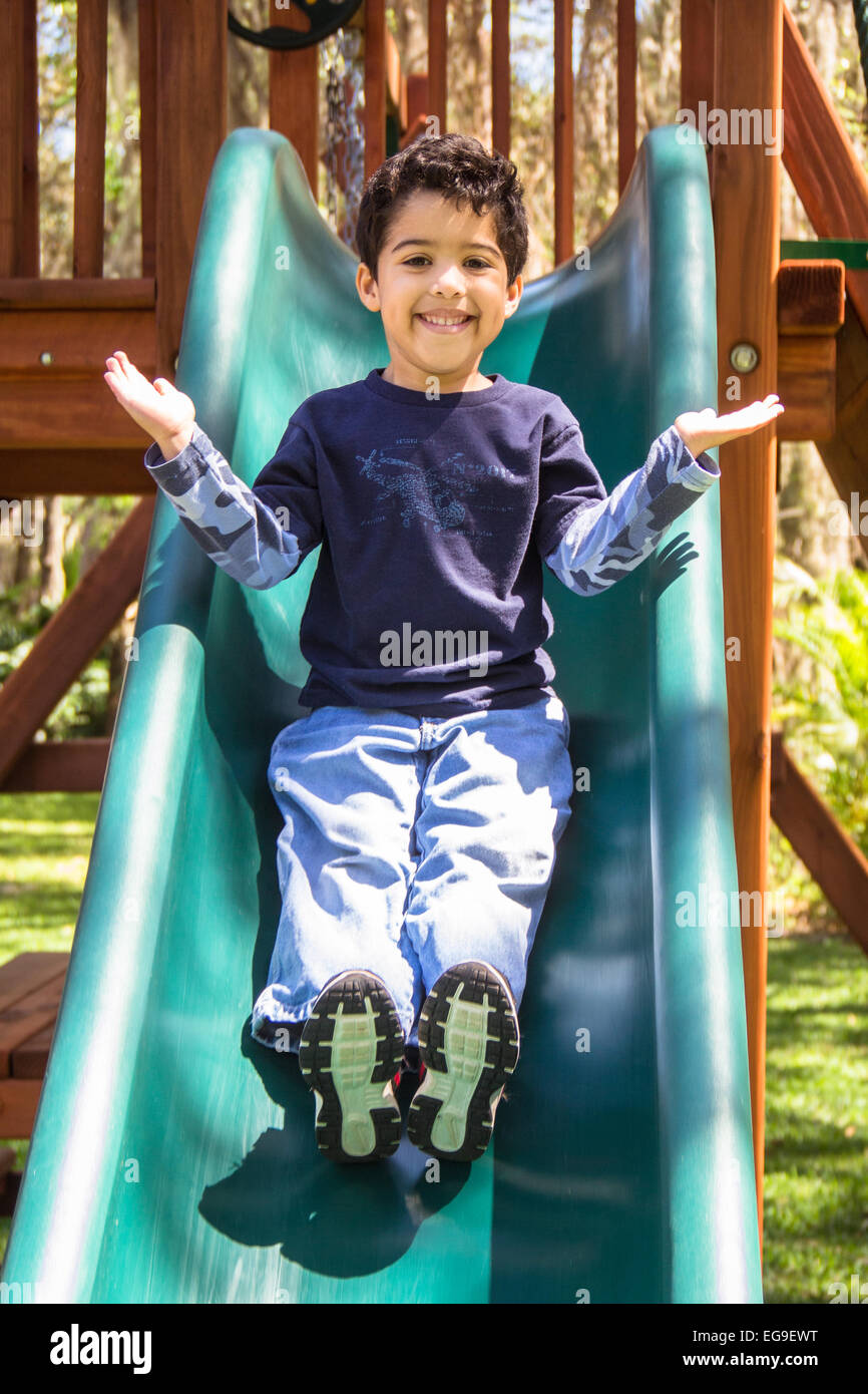 Boy in playground sliding down a slide Stock Photo