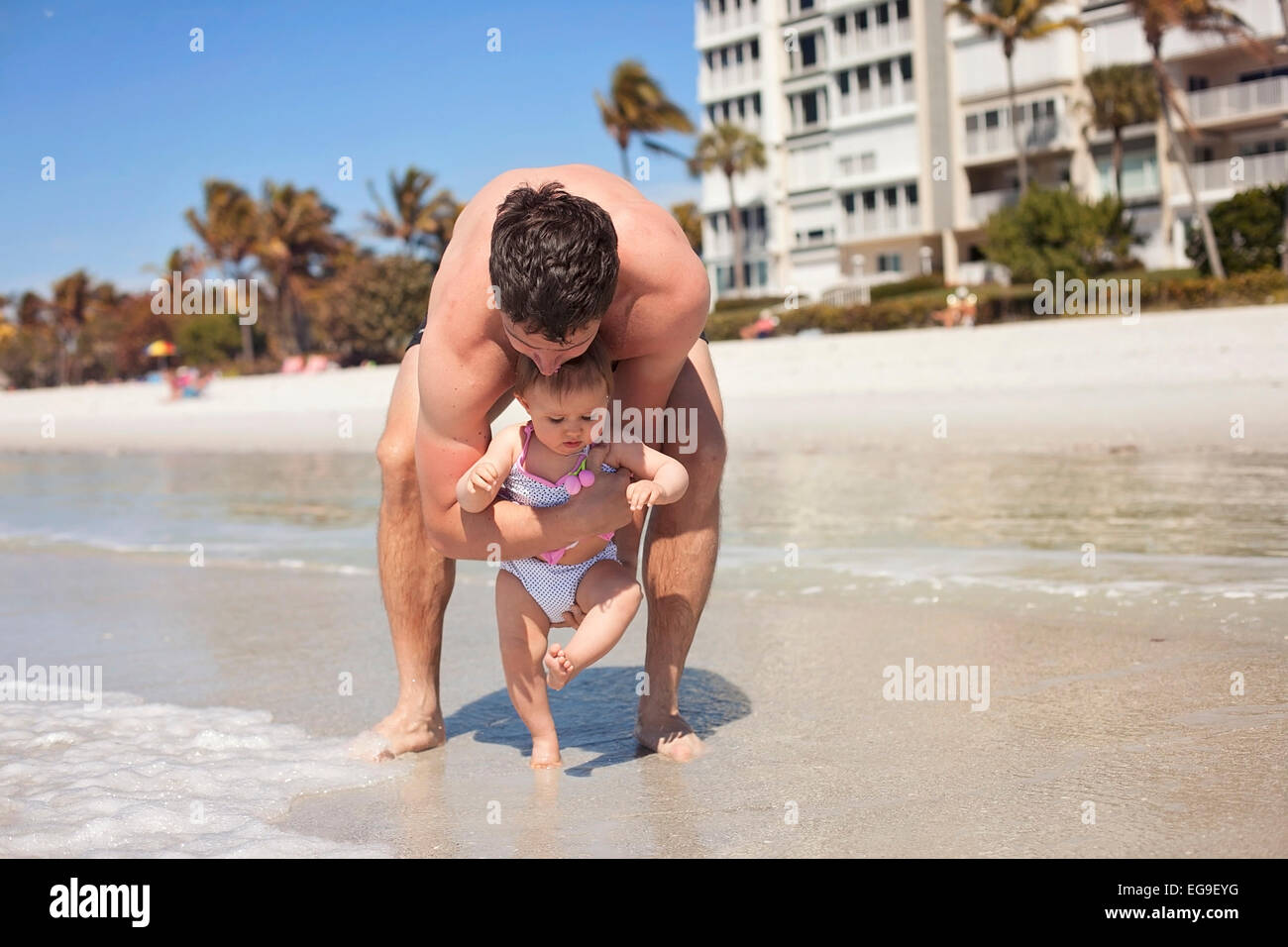 Father playing with daughter (6-11 months) on beach Stock Photo