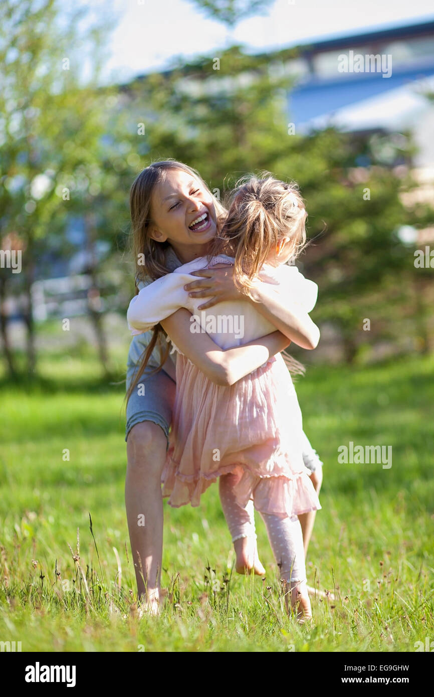 Iceland, Girls (2-3, 10-11) hugging in meadow Stock Photo