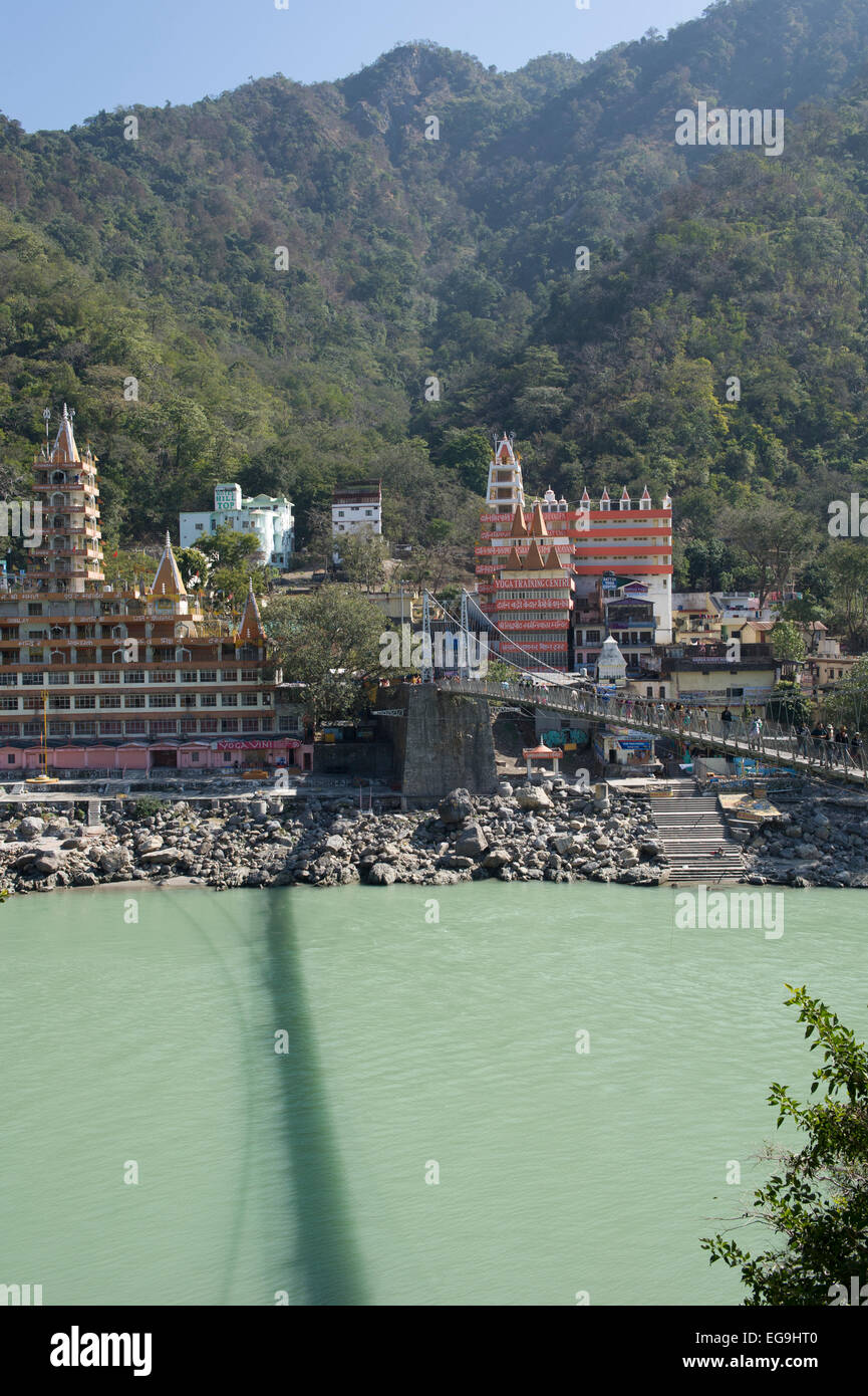 The Temples and mountains of Rishikesh with Lakshman Jhula bridge in the foreground which crosses the Ganges or Ganga river. Stock Photo