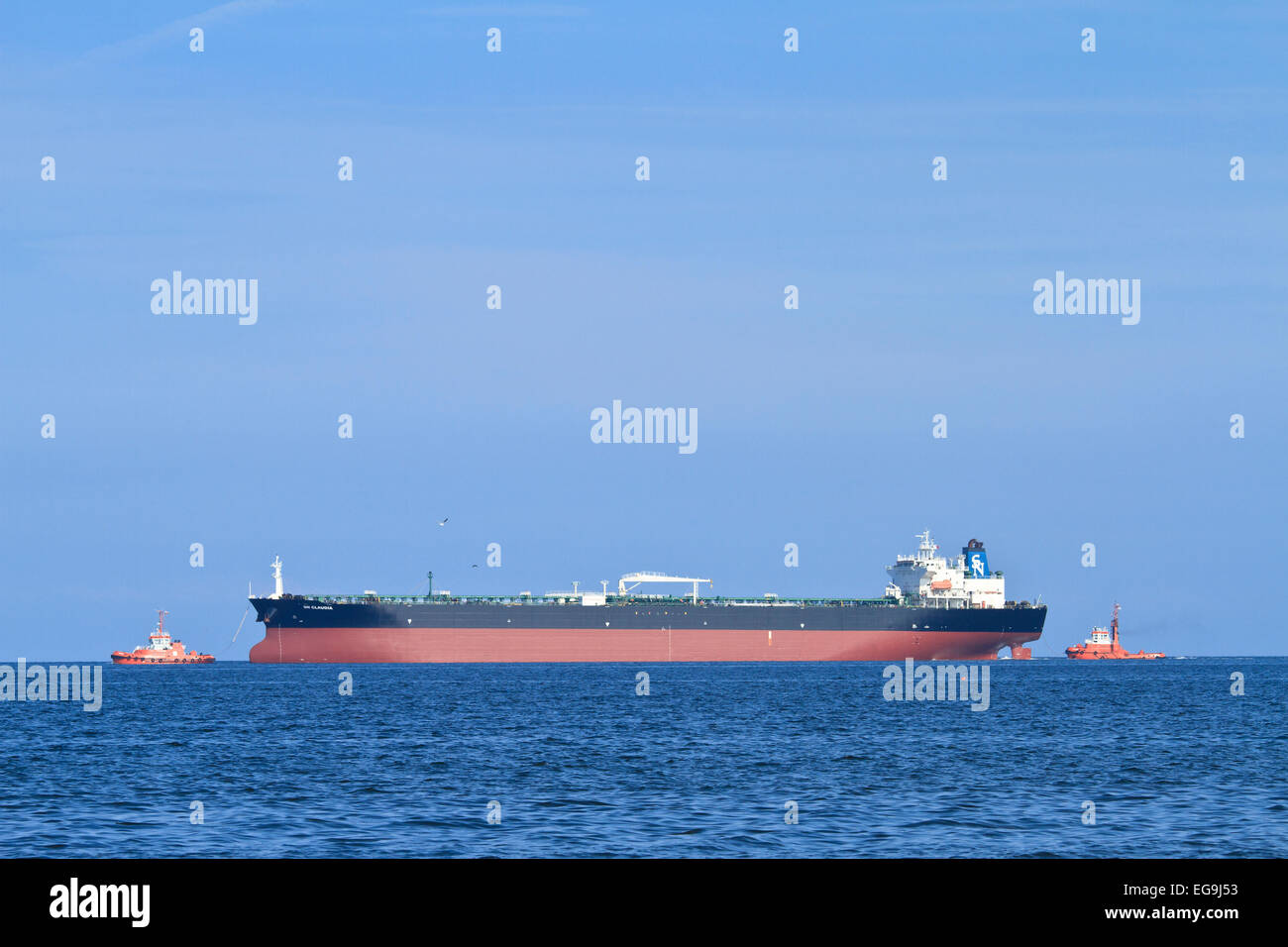 Two tug boats are moving the ship from the harbor to the sea. Stock Photo