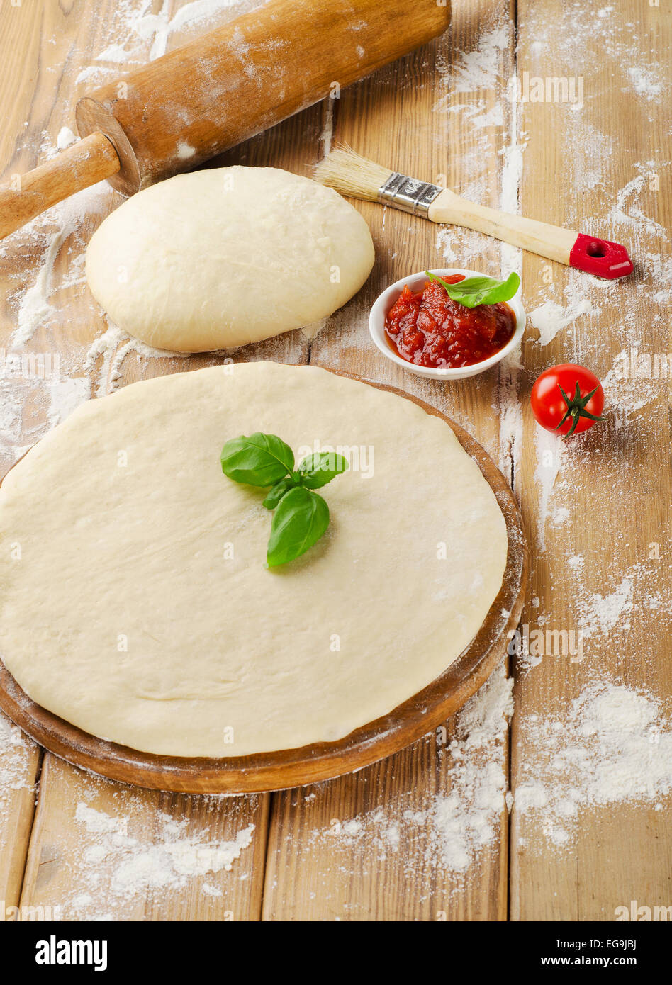 pizza dough with tomato sauce on  wooden table Stock Photo