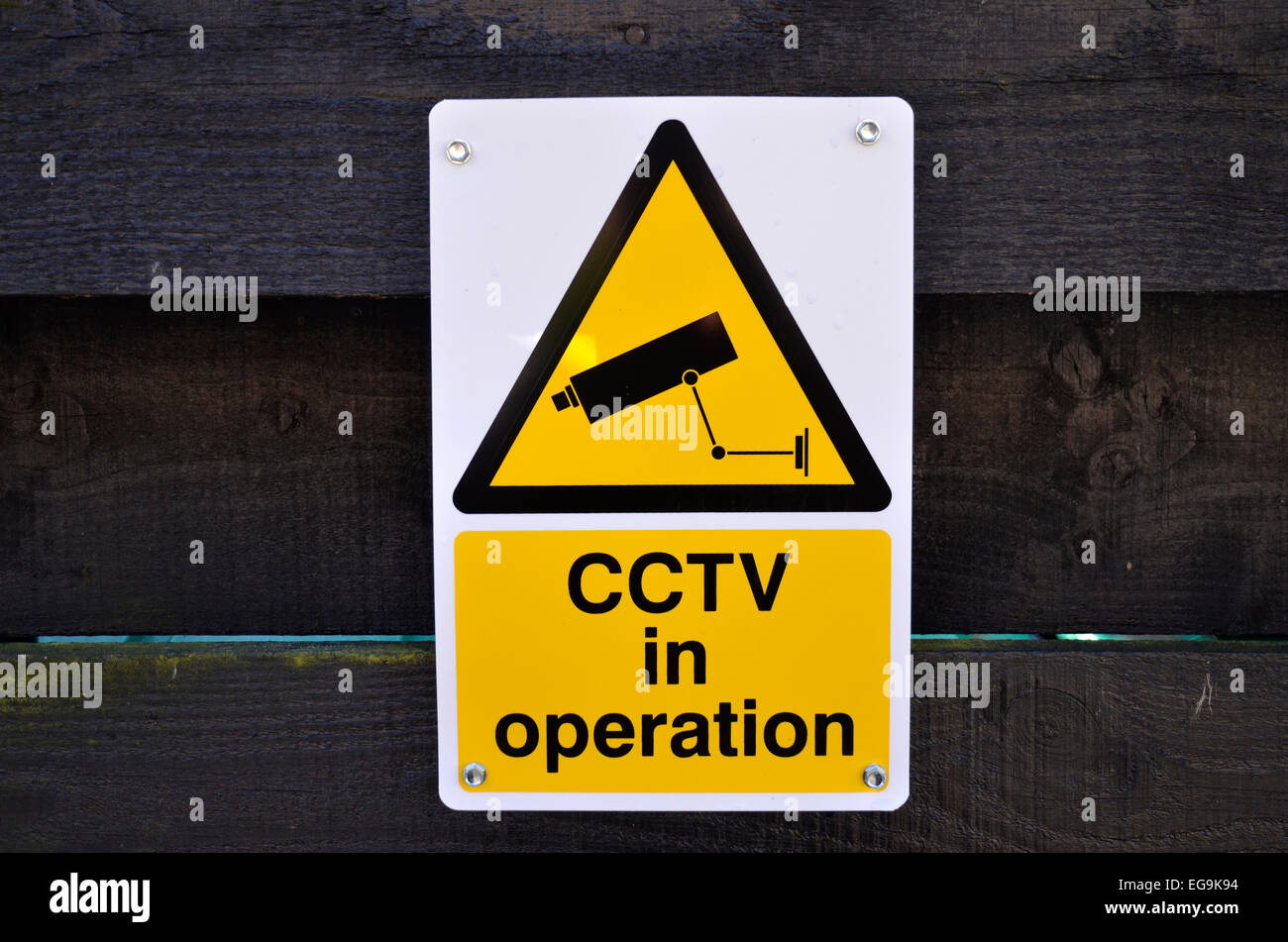 A CCTV camera sign on a wooden fence Stock Photo
