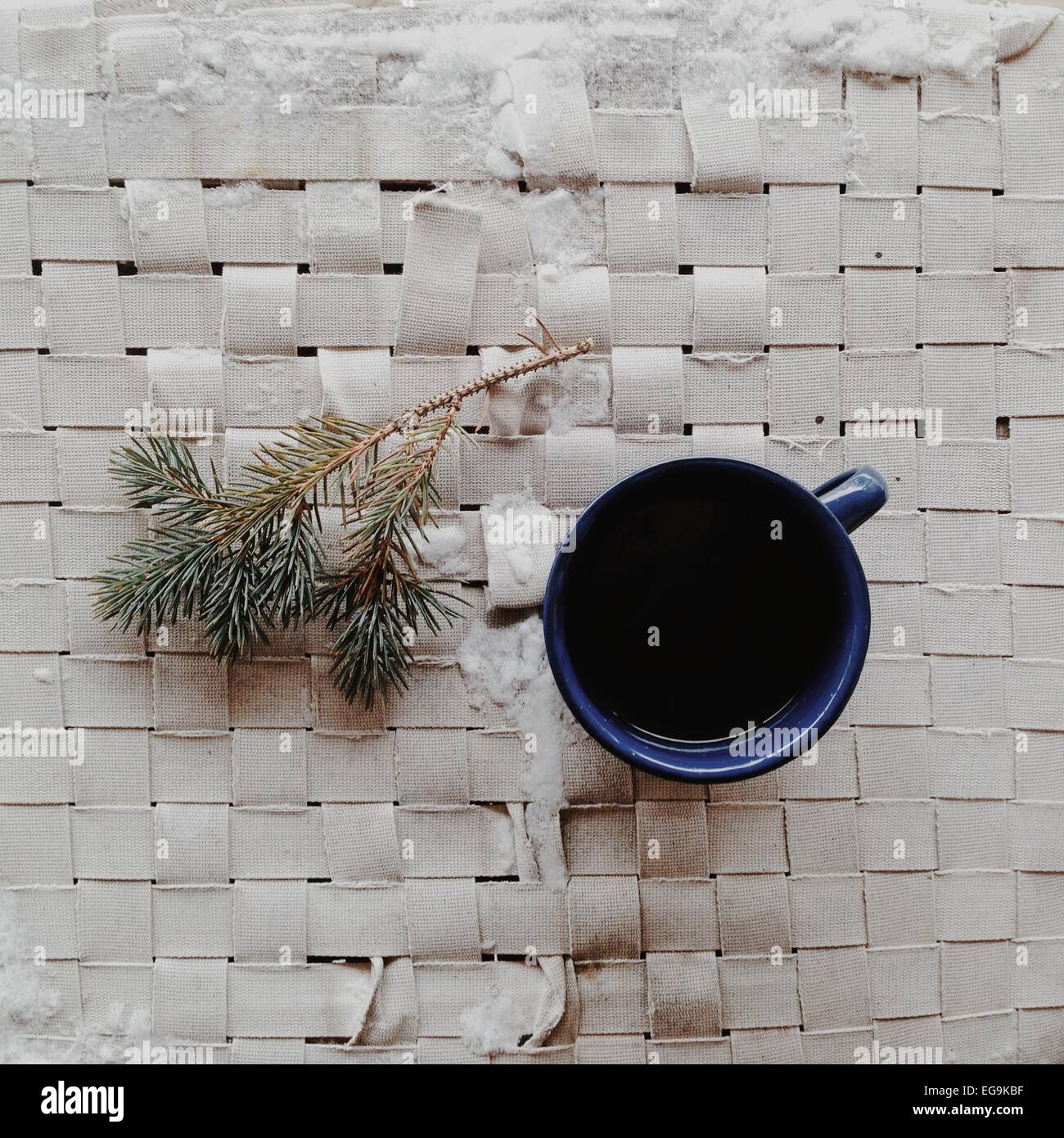 Mug of coffee and pine twig on place mat in the snow Stock Photo