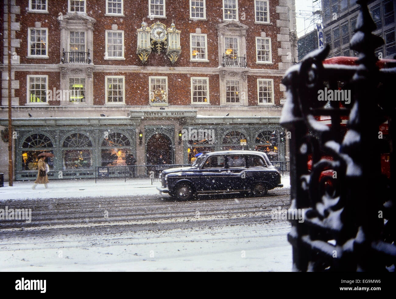 Black taxi cab passing Fortnum & Mason during a snow shower. Piccadilly. London. UK Stock Photo