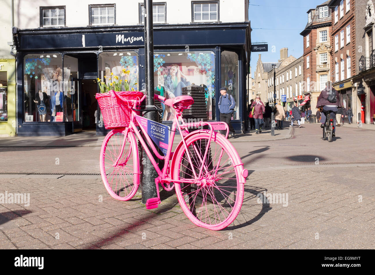 Advertising sign on parked pink bicycle Sidney Street Market Hill junction Cambridge Cambridgeshire England Stock Photo