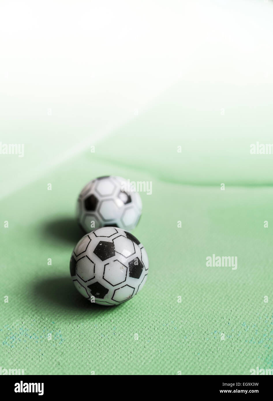 Two toy footballs in lineup on green canvas fading out to white. Vertical image with copy space. Stock Photo