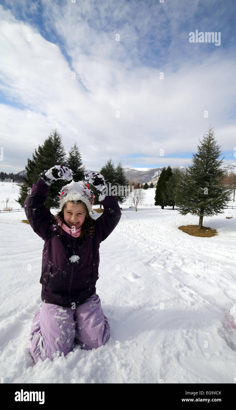 pretty little girl with wool beret playing on snow in the winter in the mountains Stock Photo