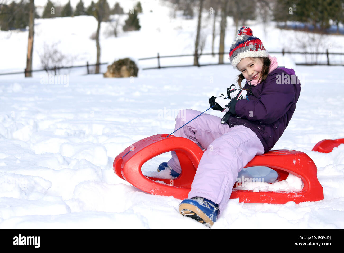 pretty girl plays with the Red sled on the snow in the winter Stock Photo