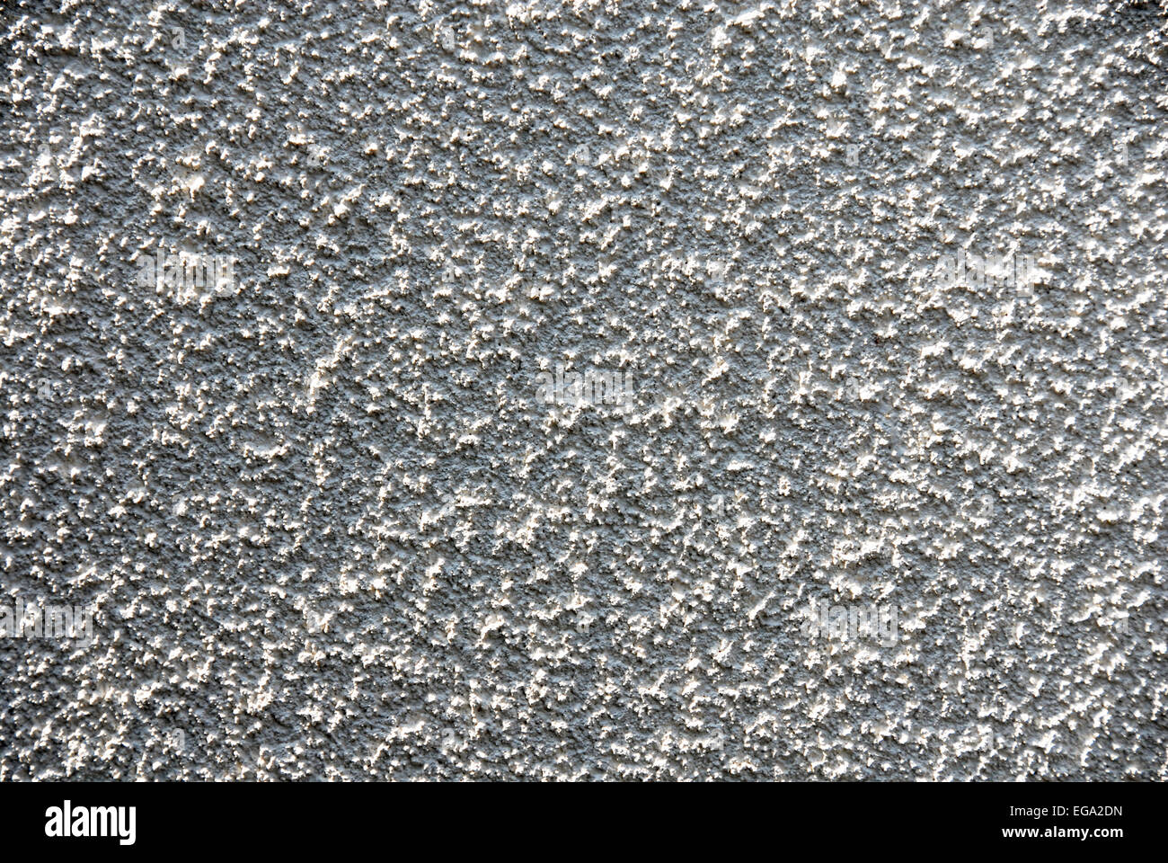 Abstract of rough pebble-dashed wall in glancing sunshine Stock Photo