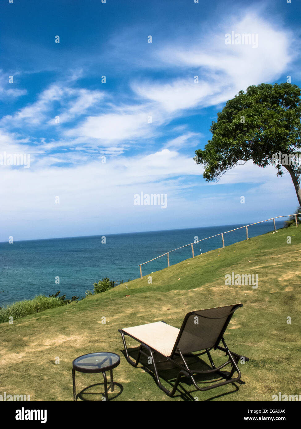 A chair and a table set on a mountain overlooking the Caribbean sea. Stock Photo