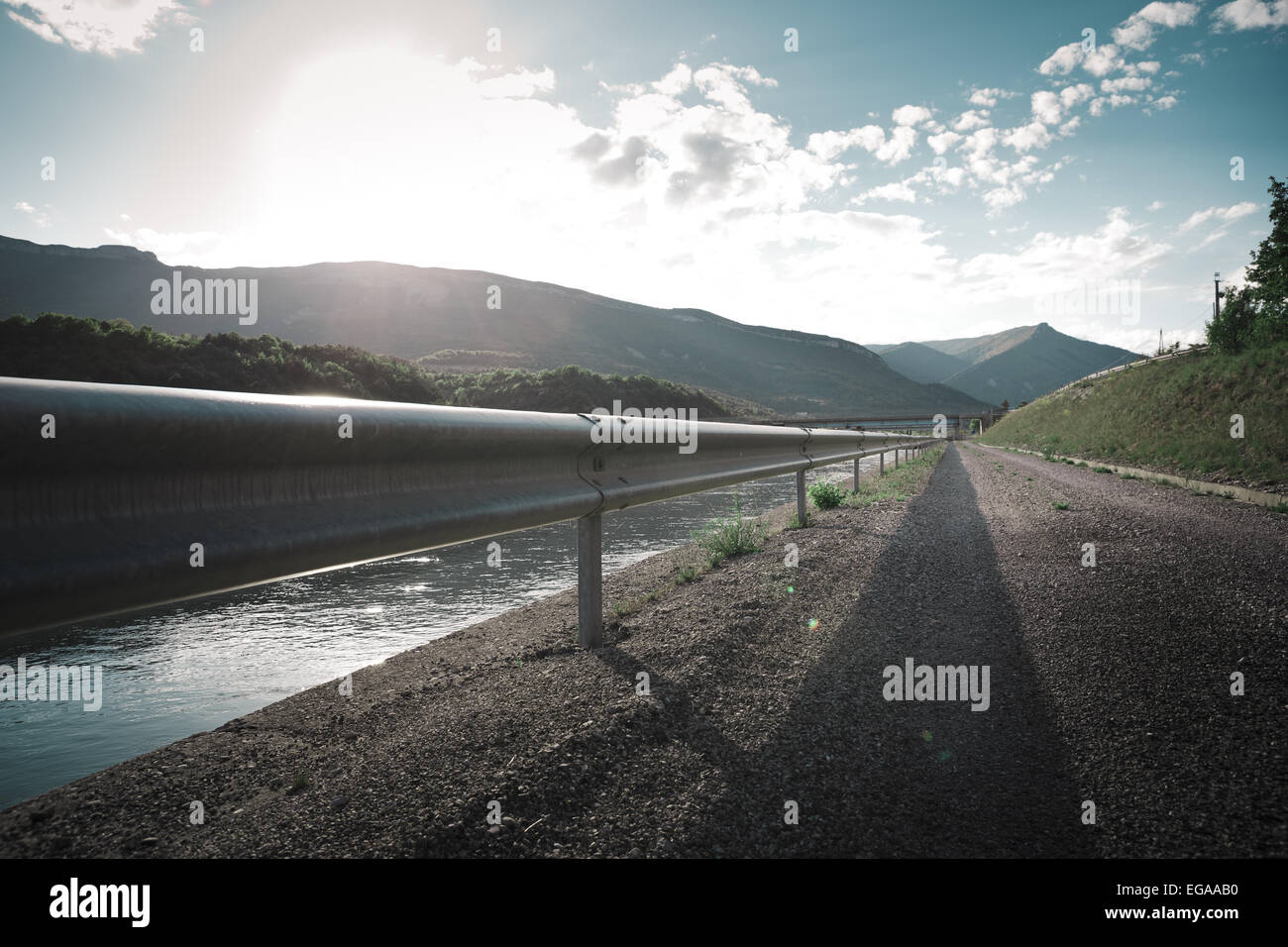 Mountains, road, crash barrier and canal, Hautes-Alpes, France. Stock Photo
