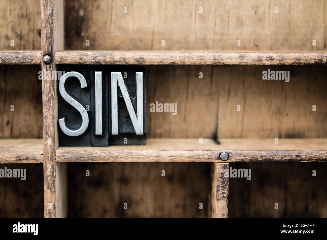 The word 'SIN' written in vintage metal letterpress type in a wooden drawer with dividers. Stock Photo