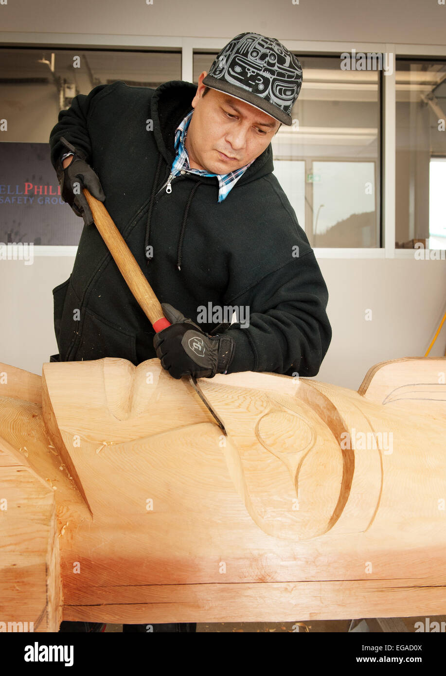 Master carver Chief Ray Natraoro, or Ses Siyam, works on a welcome figure totem pole.  Squamish BC, Canada. Stock Photo